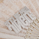 Metallic lettering on a textured surface with lace
