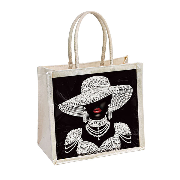 Beige tote bag with a graphic of a woman wearing a diamond-studded hat and jewelry on a black background.
