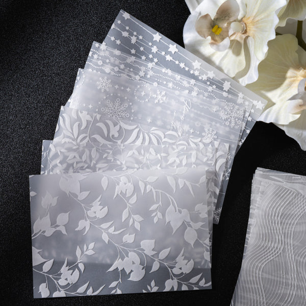 Set of translucent paper sheets with floral patterns on a black surface.