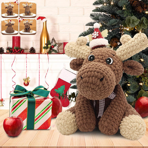 Knitted moose toy with a Santa hat in front of a Christmas tree and decorated fireplace.