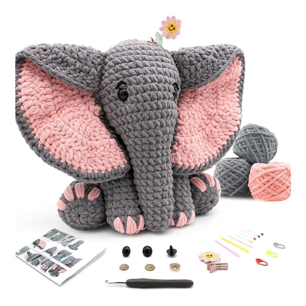 Crocheted elephant toy with yarn balls, a pattern sheet, and crochet tools on a white background