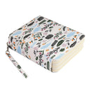 A hardcover notebook with a white cover decorated with a colorful tropical leaf and floral pattern, featuring a matching wrist strap and a stack of cream-colored pages.