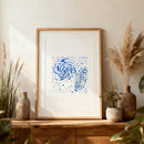 Framed artwork with blue abstract design on a wooden shelf with decorative plants.