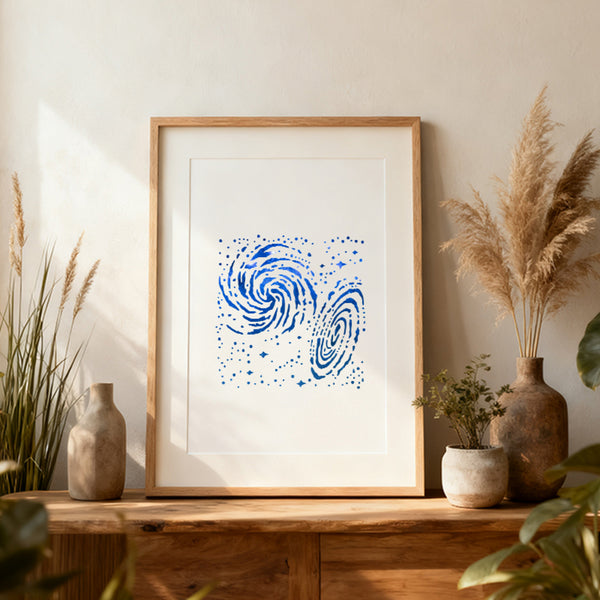 Framed artwork with blue abstract design on a wooden shelf with decorative plants.