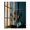 Colorful hanging decorative item on a wall with a window and plant in the background