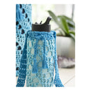 Blue crocheted scarf with tassels draped over a black container on a white background