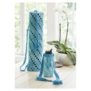Blue crochet yoga mat bag and water bottle holder on a light wooden floor with a plant in the background.