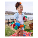 Child holding a wooden basket with colorful vegetables outdoors by a lake.