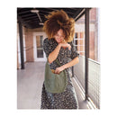 Woman holding a green handbag on a covered outdoor patio