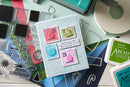 Card with postage stamp designs surrounded by stamping supplies on a light blue background