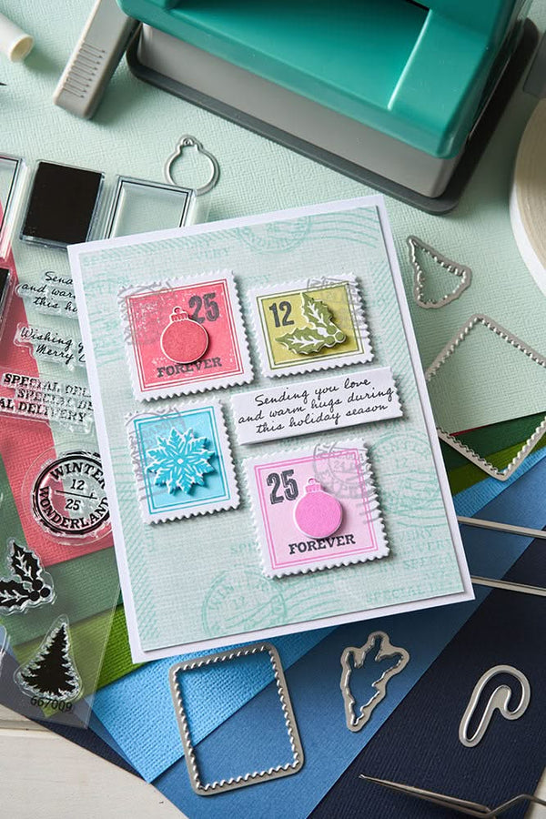 Card with postage stamp designs on a crafting table with stamps and dies.