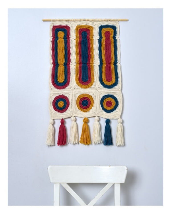 Colorful woven wall hanging with tassels on a light blue background