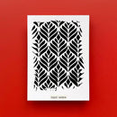 Decorative stencil with black leaf pattern on a white background, against a red wall.