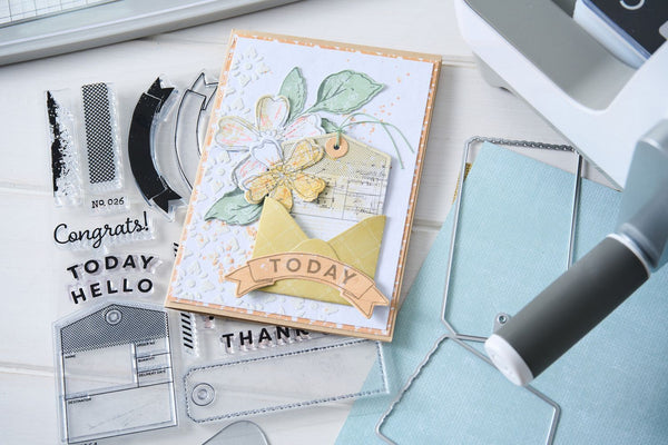 Handmade card with floral design on a crafting table with tools and stamps.