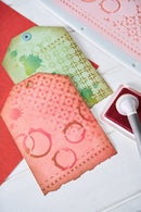 Two decorative paper tags with a stamp and ink pad on a white surface