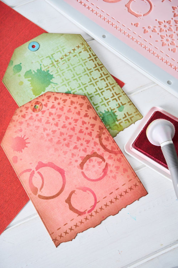 Two decorative paper tags with a stamp and ink pad on a white surface