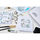 Collection of birthday cards with artistic designs on a white surface with art supplies.