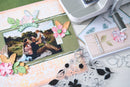 Scrapbooking project with photo, decorative elements, and a printer on a table.