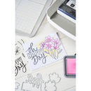 Card with 'Happy Day' text and flowers, surrounded by stamping tools on a white surface.