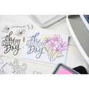 Card with 'Happy Day' text and floral design on a desk with stamping tools.