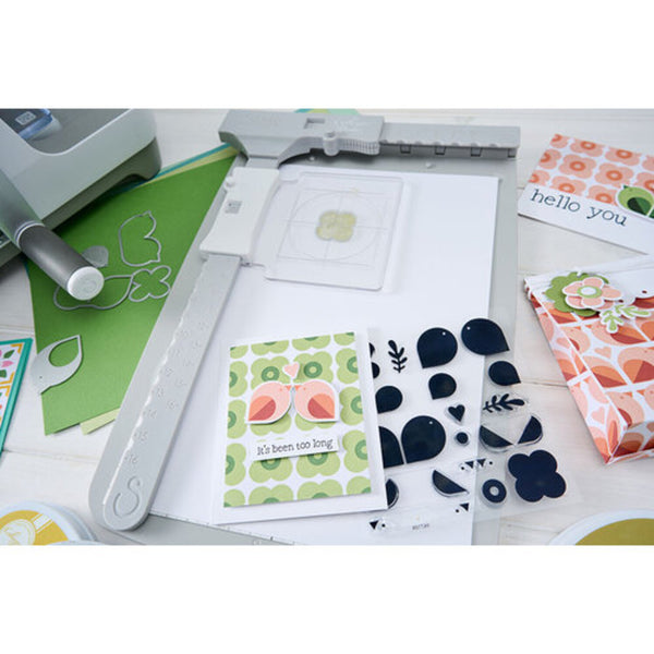 Card-making supplies including stamps, dies, and printed cards on a white surface.