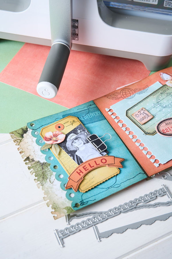 Card with decorative elements on a cutting mat with a craft knife and ruler.