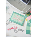 Colorful 'happy birthday' card with stamping tools on a white surface