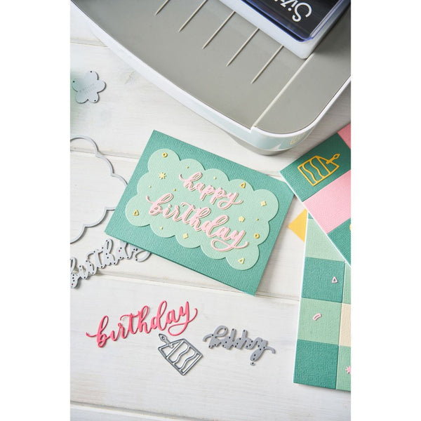 Colorful 'happy birthday' card with stamping tools on a white surface