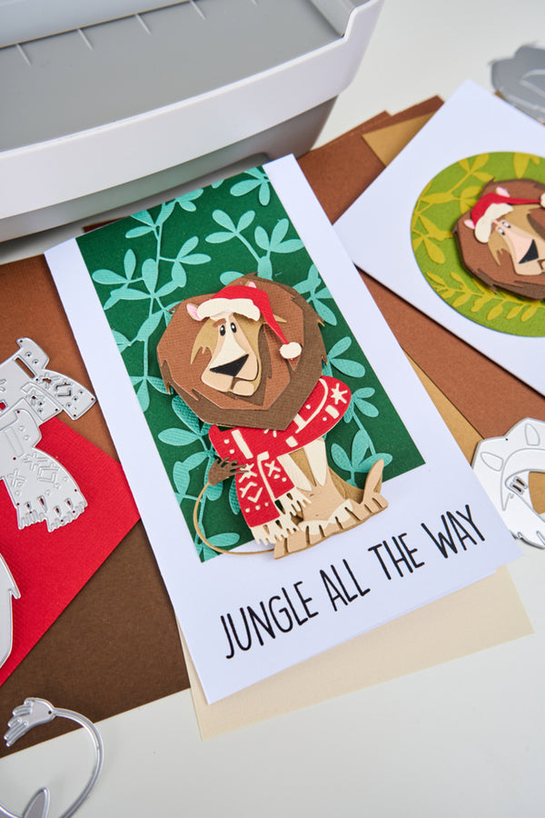 Card with a lion wearing a Santa hat and text 'Jungle All The Way' on a table with other cards.