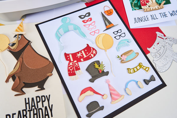 Sheet of birthday-themed cutouts with hats, scarves, and balloons on a white background.