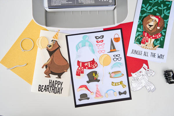 Card with bear illustration and birthday text, surrounded by stationery items on a light gray background.
