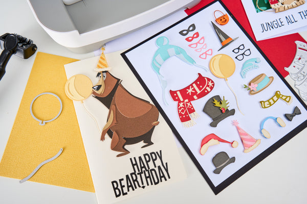 Birthday card with bear illustration and party hats on a printer bed