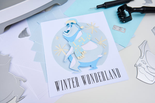 Card with a snowman design and 'Winter Wonderland' text, surrounded by crafting tools on a light surface.