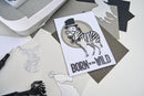 Card with zebra wearing a top hat and bow tie, text 'Born to be Wild', surrounded by paper cutouts on a light background.