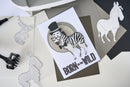Card with zebra illustration and 'Born to be Wild' text, surrounded by paper cutouts of animals.