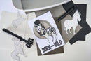 Card with zebra illustration and 'Born to be Wild' text on a white surface with cut-out animal shapes.