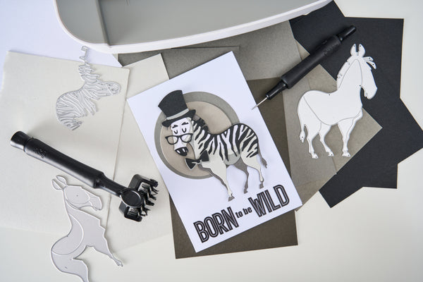 Card with zebra illustration and 'Born to be Wild' text on a white surface with cut-out animal shapes.