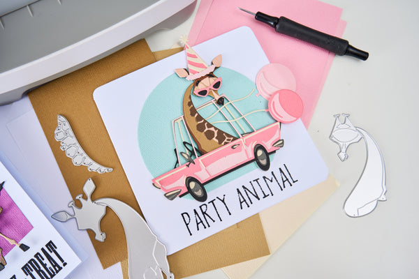 Card with a giraffe in a pink car and 'Party Animal' text on a crafting surface.
