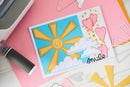 Colorful card with sun and heart design on a pink surface with craft supplies.