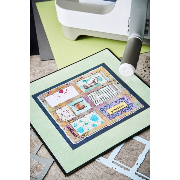 Decorative card with various designs on a green mat next to a crafting tool.