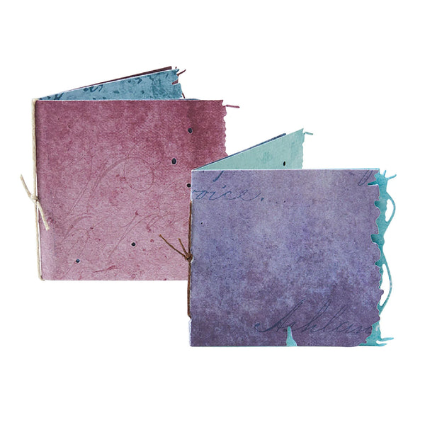 Two handmade notebooks with textured covers and string closures on a white background
