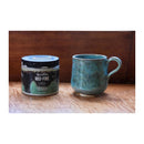 Ceramic mug and container labeled 'Mid-Fire Dragon Stone' on a wooden surface with a wooden panel background.