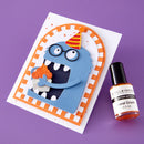 Card with a blue monster holding a cupcake and a bottle of nail polish on a purple background