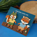 Two fox characters on a card with 'Camp More, Worry Less' text, surrounded by nature-themed elements.
