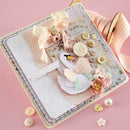 Decorative notebook with swan design and embellishments on a pink background