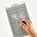 Hand using a die-cutting tool on a grid cutting mat with 'Sellebrity' branding.