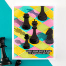 Colorful geometric patterned card with black chess pieces and motivational text on a teal background.