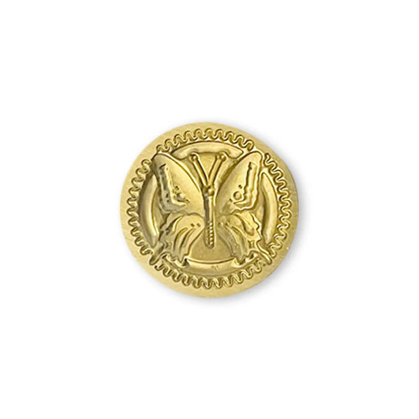 Gold-colored decorative button with a design on a white background