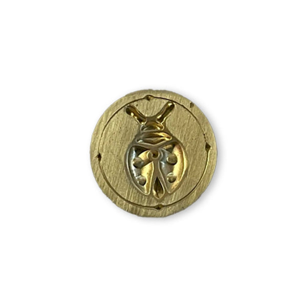 Gold decorative button with intricate design on a white background