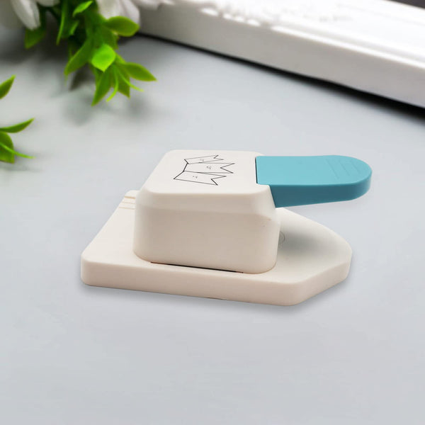 White and blue paper punch on a light gray surface with green leaves in the background